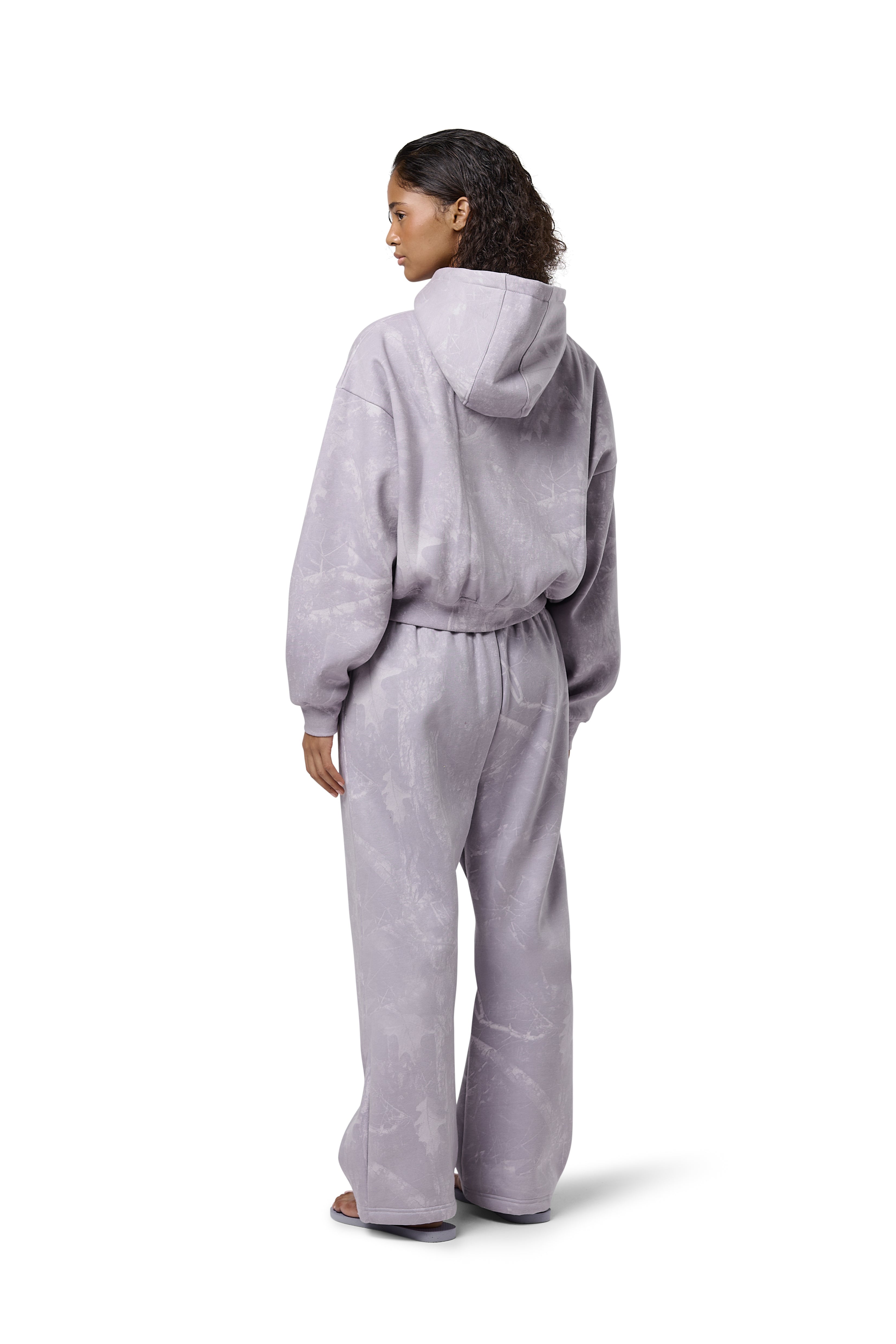 Lilac high-waisted straight-leg sweatpants with subtle twig camo print, elasticated drawstring waist, and embroidered Sisters & Seekers logo. Soft cotton-blend fabric in sizes 2XS–3X, available in Petite, Regular, and Tall lengths
